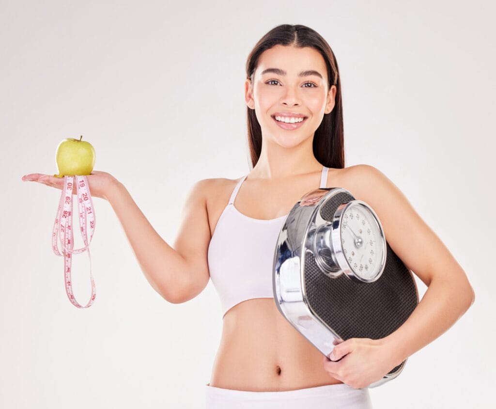 Woman holding scale, happy about weight loss